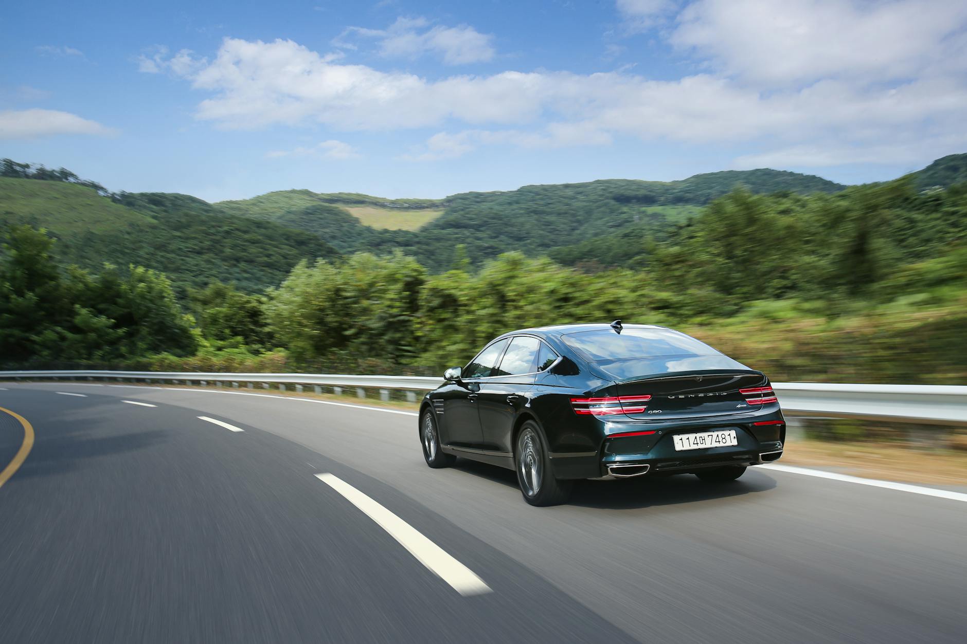 Czarny sedan jedzie krętą drogą w górach latem