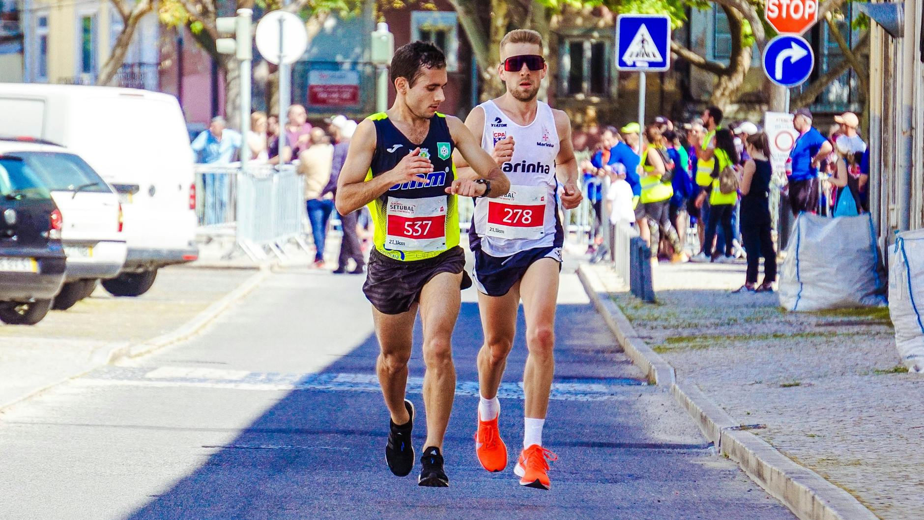 Dwóch biegaczy rywalizuje w miejskim maratonie w słoneczny dzień