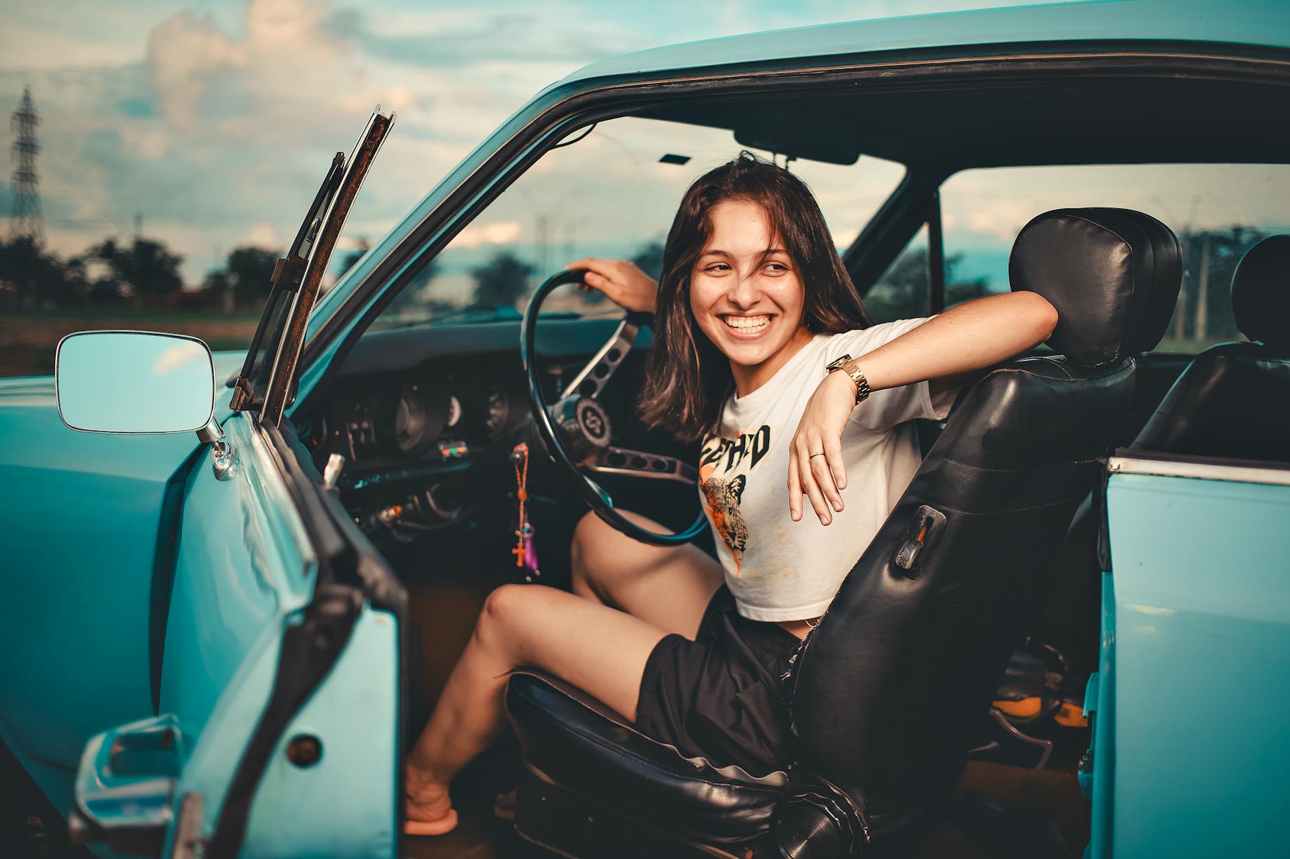 Młoda kobieta w niebieskim kabriolecie BMW podczas jazdy w słoneczny dzień