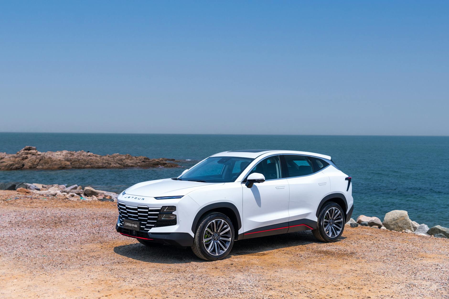 Biały SUV Changan zaparkowany nad morzem w słoneczny dzień