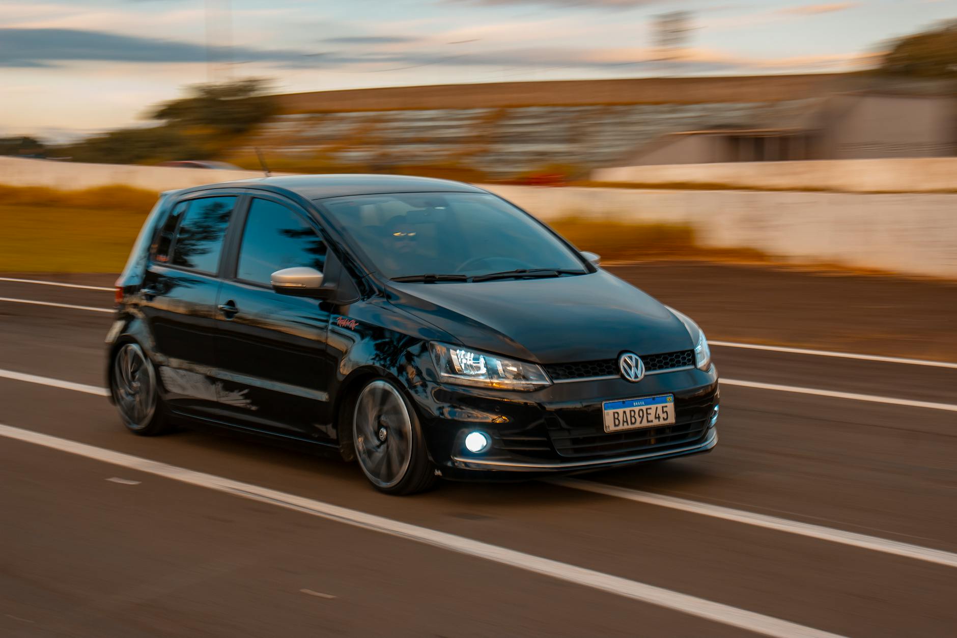 Czarny hatchback jadący szybko po szosie w słoneczny dzień