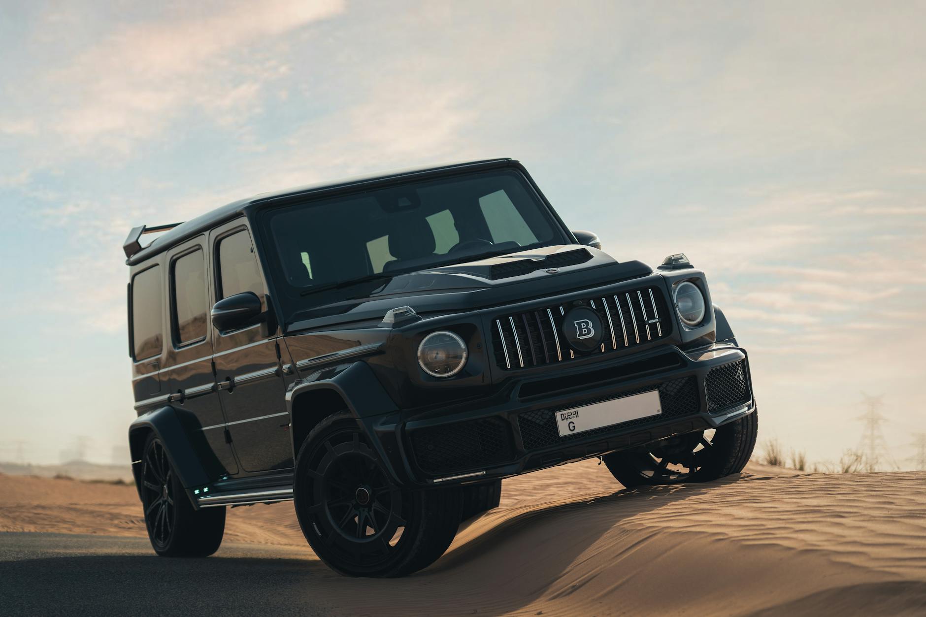 Czarny SUV klasy premium jedzie po pustynnych wydmach o zmierzchu
