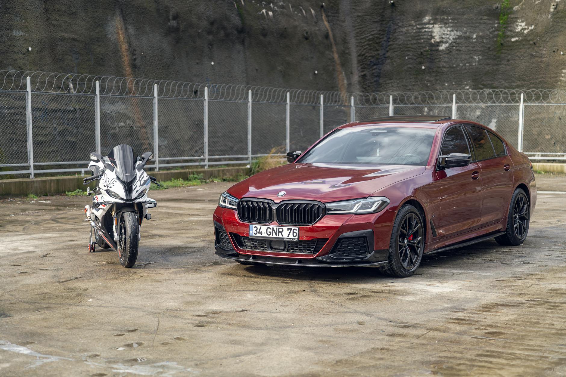 Czerwony luksusowy sedan i sportowy motocykl na betonowym parkingu