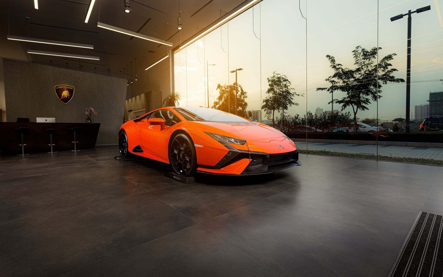Pomarańczowe Lamborghini Huracan w nowoczesnym salonie samochodowym