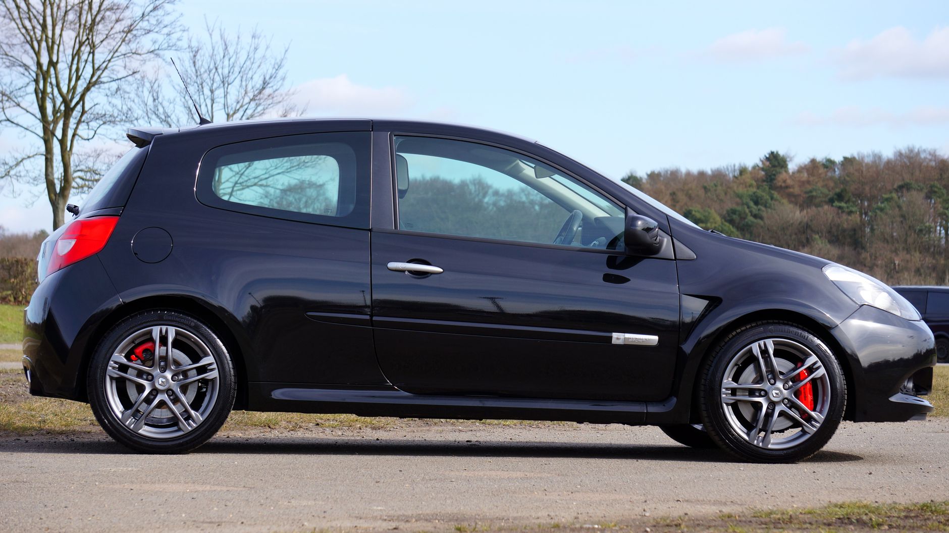 Czarne Renault Clio RS zaparkowane wśród drzew