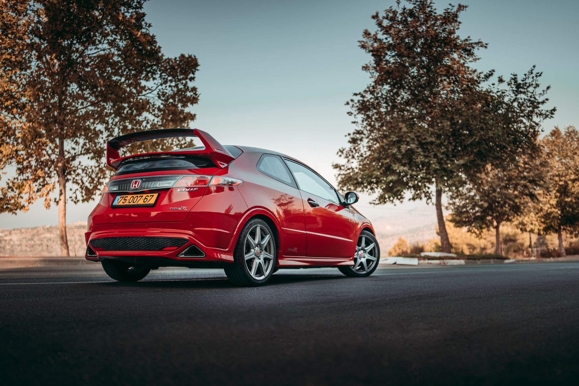 Czerwony sportowy hatchback z tylnym spojlerem na górskiej drodze