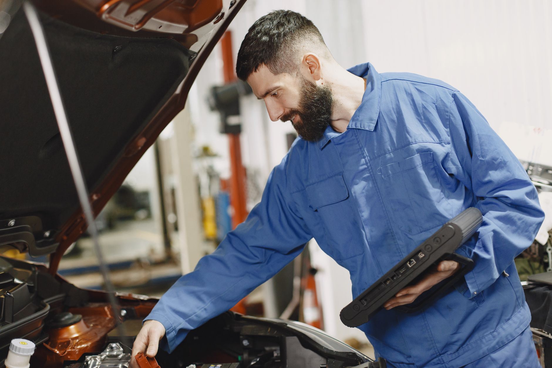Mechanik w niebieskim kombinezonie sprawdza silnik Renault w garażu